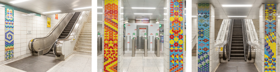 Escalator and fare gates with decorated pillars in front of them. 